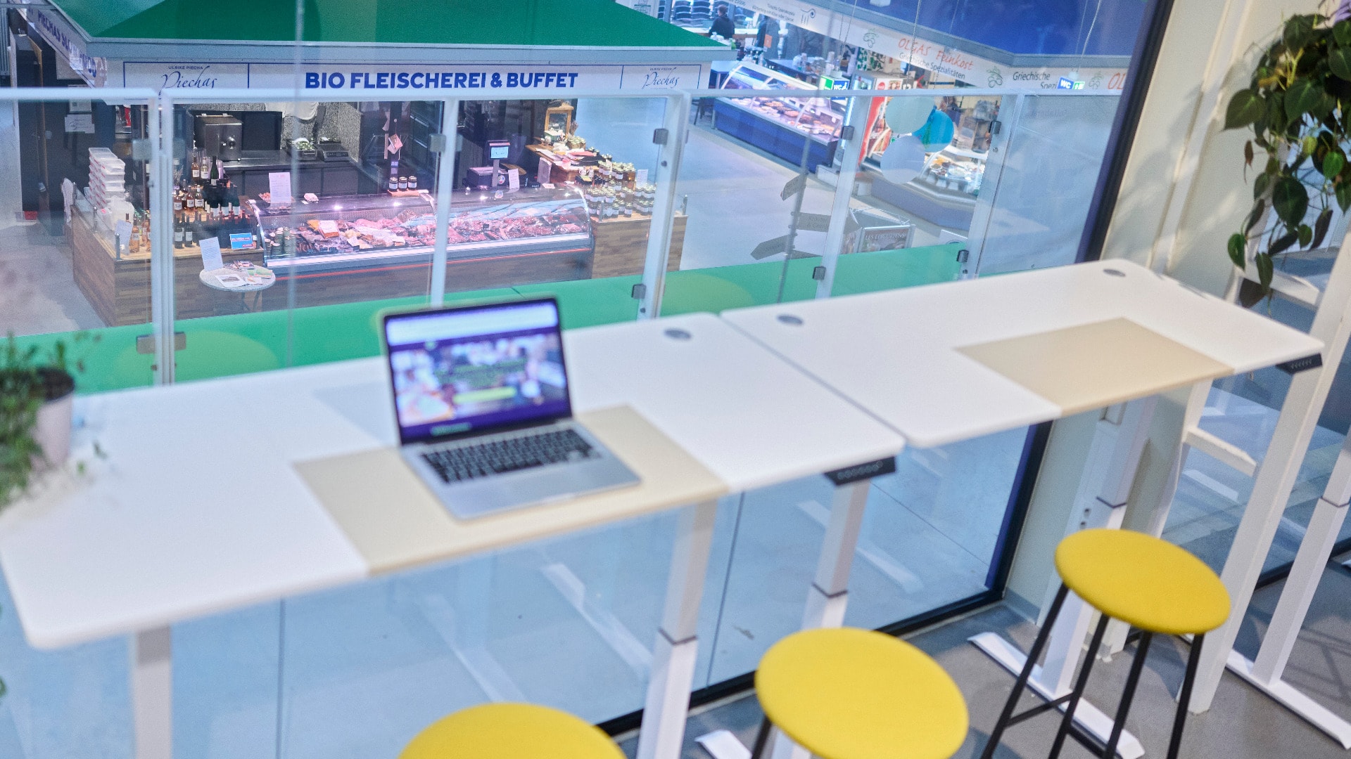 Ein Arbeitsbereich mit Hockern, dahinter ein Blick auf die Markthalle.