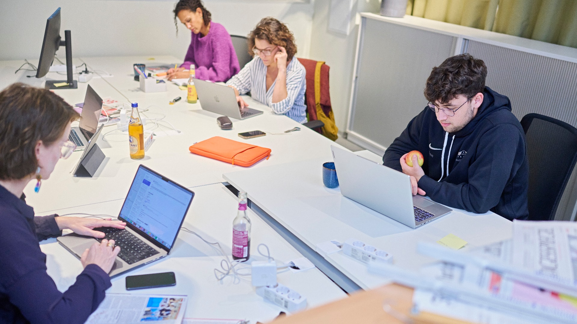 Mehrere Personen sitzen an einem Tisch und arbeiten an Computern.